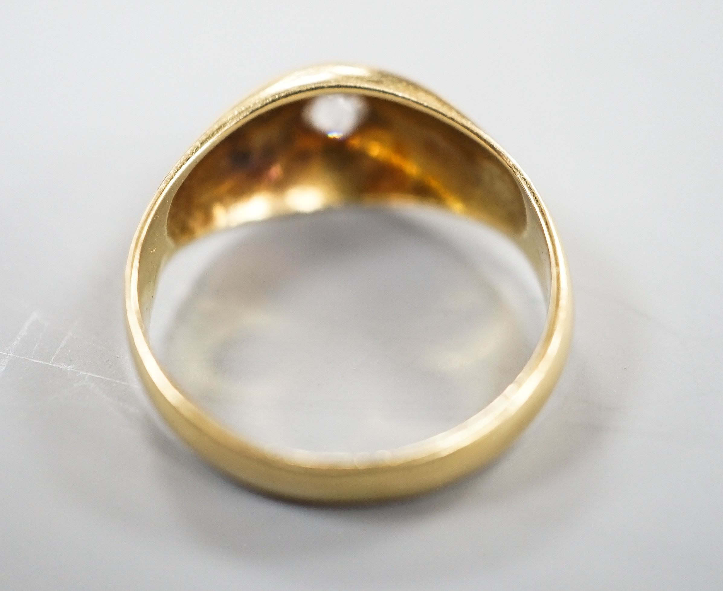 A yellow metal (stamped 18) and gypsy set solitaire diamond ring, size R, gross 5.6 grams.